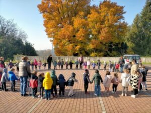 Bambini in cerchio in una piazza, sullo sfondo un albero