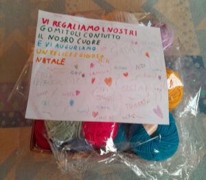 Biglietto di auguri con la scritta: Vi regaliamo i nostri gomitoli con tutto il nostro cuore