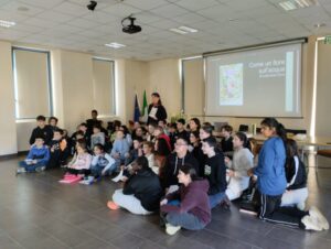 Bambini seduti in terra davanti alla proiezione Come un fiore sull'acqua