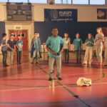 bambino in piedi al centro, intorno a lui altri bambini in piedi a semicerchio