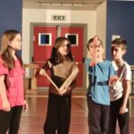 quattro bambini, uno di loro ha in mano un libro