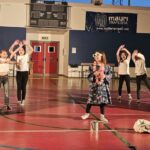 bambini divisi in due gruppi, al centro una bambina che balla