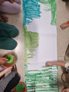 mani di bambini che colorano fogli messi a terra
