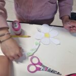 mani di bambini, un fiore di carta e un paio di forbici