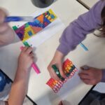 mani di bambini che colorano dei segnalibri