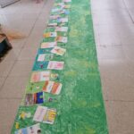cartellone verde con appoggiati fogli disegnati dai bambini