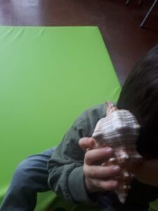bambino con una conchiglia appoggiata all'orecchio destro