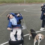 un bambino sorridente in carrozzina tiene un cane al guinzaglio