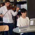 un ragazzo che suona il violino accompagnato da un altro ragazzo alla tastiera