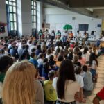 i ragazzi seduti per terra, davanti a loro un alcuni ragazzi seduti sulle sedie